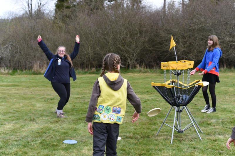 Golf frisbee - A Brownie playing with the frisbee, and a leader cheering at her success